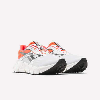 A pair of Reebok Men's FloatZig 2 Running Shoes in white with black and gray accents, orange lining, and chunky white soles with Superfloat+ cushioning, displayed side by side on a plain white background.