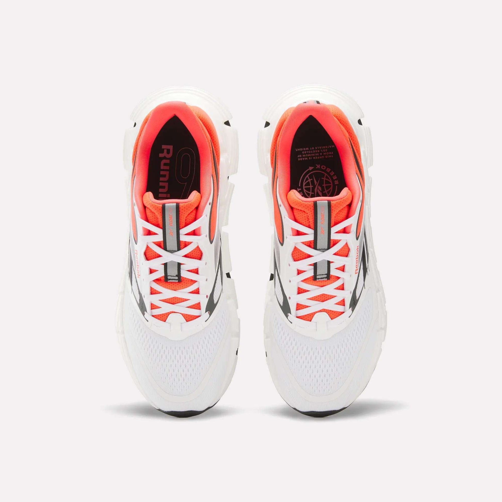 A pair of Reebok Men's FloatZig 2 Running Shoes with Superfloat+ cushioning, supportive white upper, orange inner lining, gray accents, and white laces is shown from above on a plain light background.