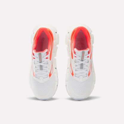 A pair of Reebok Women's FloatZig 2 Running Shoes in white, showcasing breathable mesh uppers, bold orange accents, and chunky soles with Superfloat+ cushioning for exceptional comfort—displayed from above on a light background.