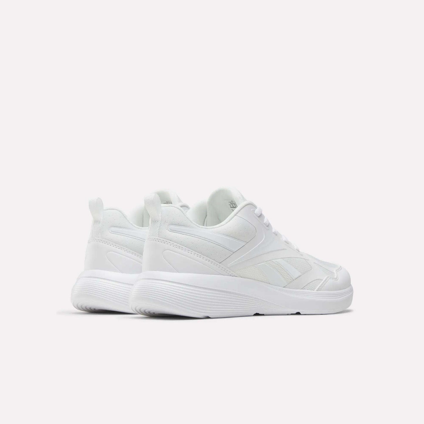 The Reebok Rush Runner 6.0 Running Shoes for big kids are white athletic sneakers with lace-up fronts, EVA midsoles, and textured soles, displayed on a plain white background to show their sides and backs.