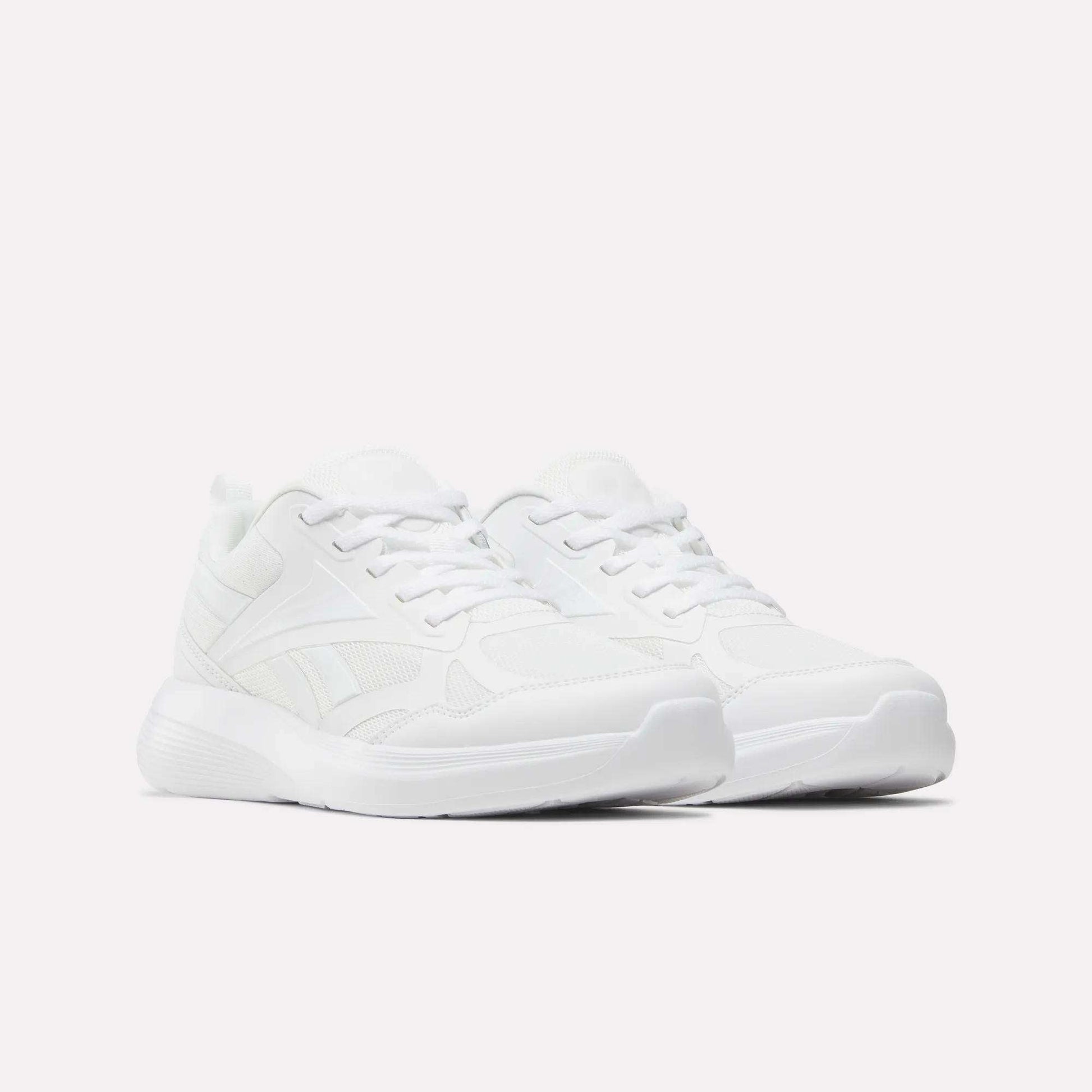 A pair of all-white Reebok Rush Runner 6.0 Running Shoes for big kids, featuring laces, mesh, and synthetic material, displayed on a plain white background.