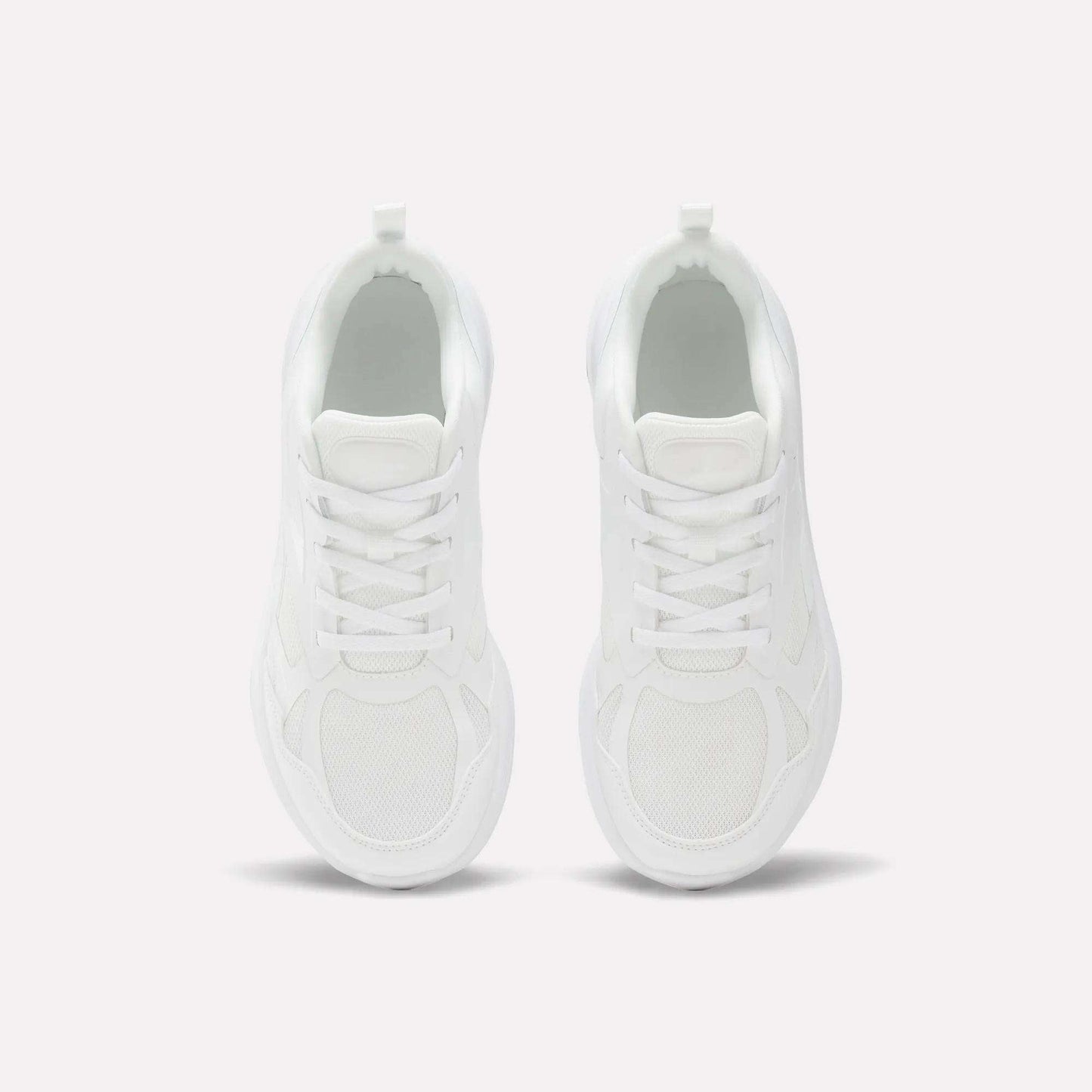 Top view of Reebok Rush Runner 6.0 Running Shoes for big kids, in clean white with white laces, minimalist design, and EVA midsole, placed side by side on a light background.