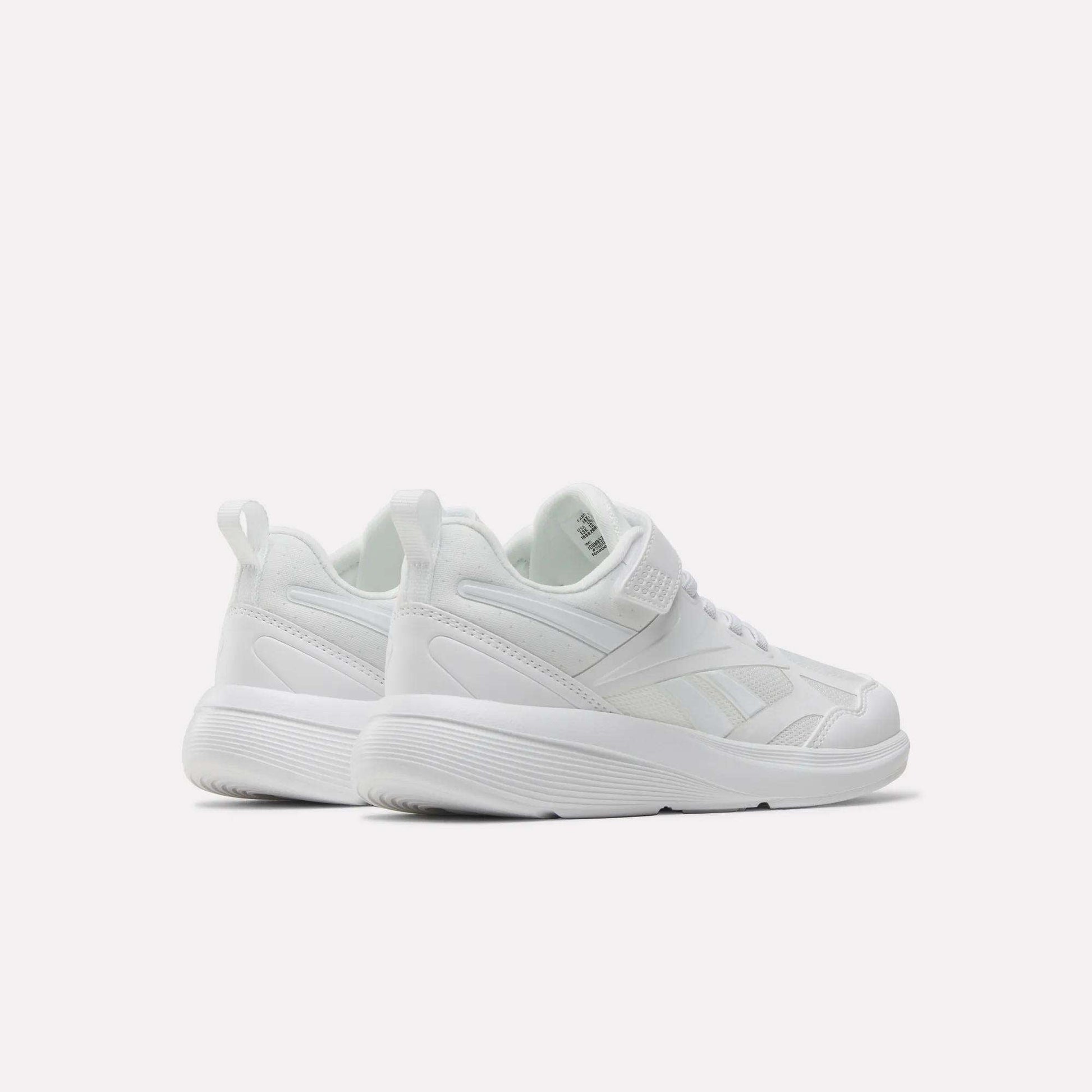 The Reebok Rush Runner 6.0 Elastic Lace Top Strap Running Shoes for little kids are white with thick soles, mesh and leather details, pull tabs at the back, and are designed for all-day comfort—displayed on a plain white background.