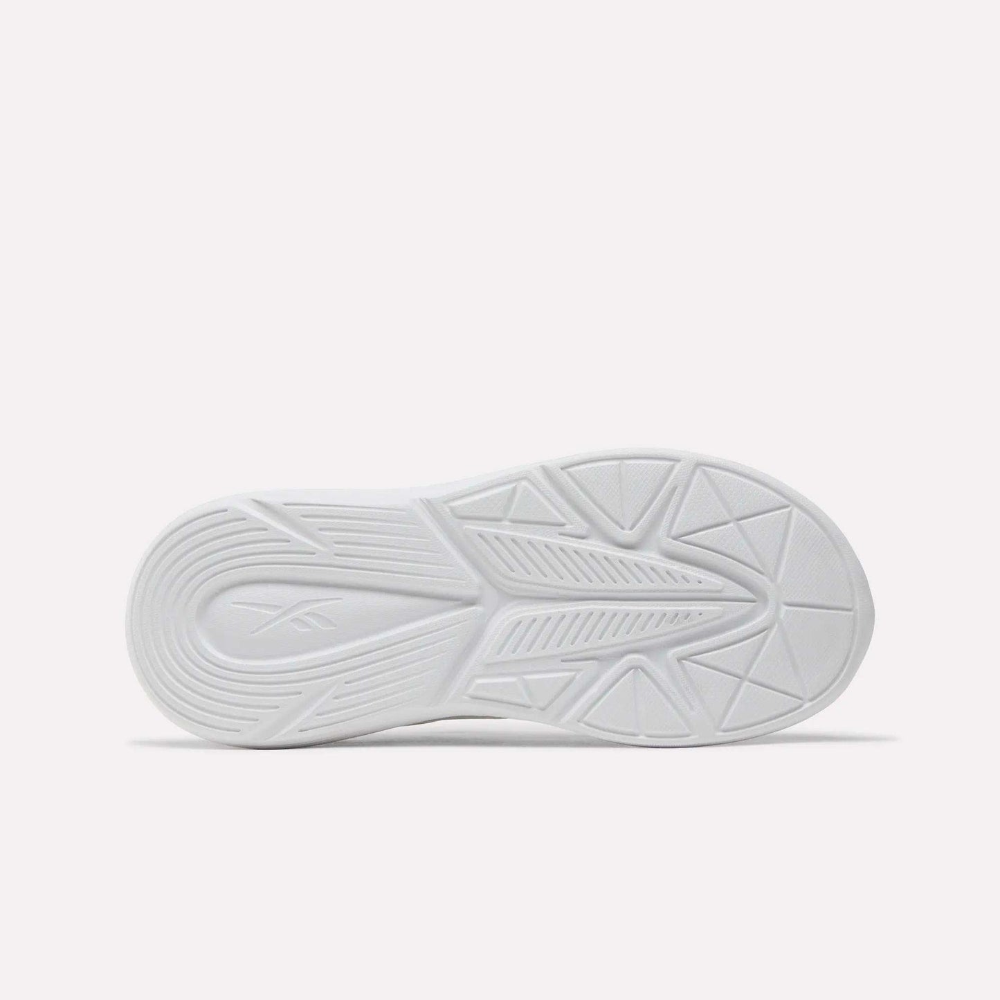 The image shows the bottom view of a white Reebok Rush Runner 6.0 Elastic Lace Top Strap Running Shoe for little kids, featuring geometric tread patterns and an embossed Reebok logo on the left, plus EVA cushioning for comfort. The background is plain and light-colored.
