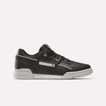 The Reebok Workout Plus Shoes are black leather low-tops with a white sole and subtle white and gray accents. Stylish for workouts, they display the Reebok logo and flag on the side.