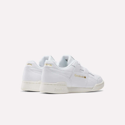 A rear side view of Reebok Workout Plus Shoes in white with gold branding, off-white soles, and classic low-top ‘80s fitness style on a plain white background.
