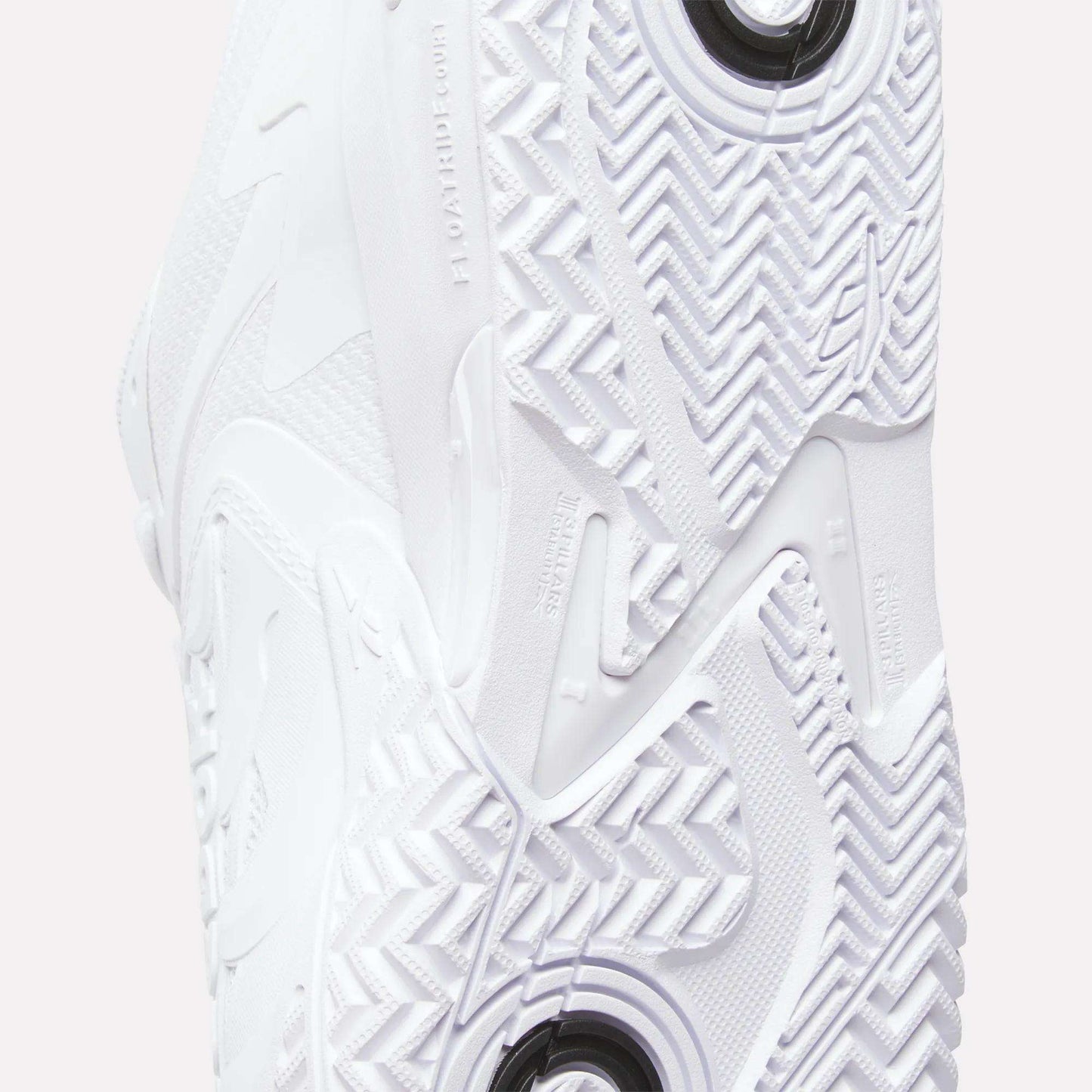 Close-up of the Reebok Phase EVO Tennis Shoes sole, showcasing detailed textured patterns, grooves with circular and zigzag designs, and embossed branding—highlighting the durable features of these tennis shoes.