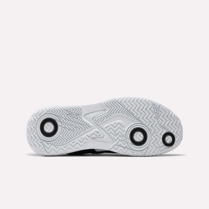 The image features the sole of Reebok Women's Phase Evo Tennis Shoes, displaying a herringbone tread, circular grip accents, and a raised midsection for durability, all set against a plain white background.