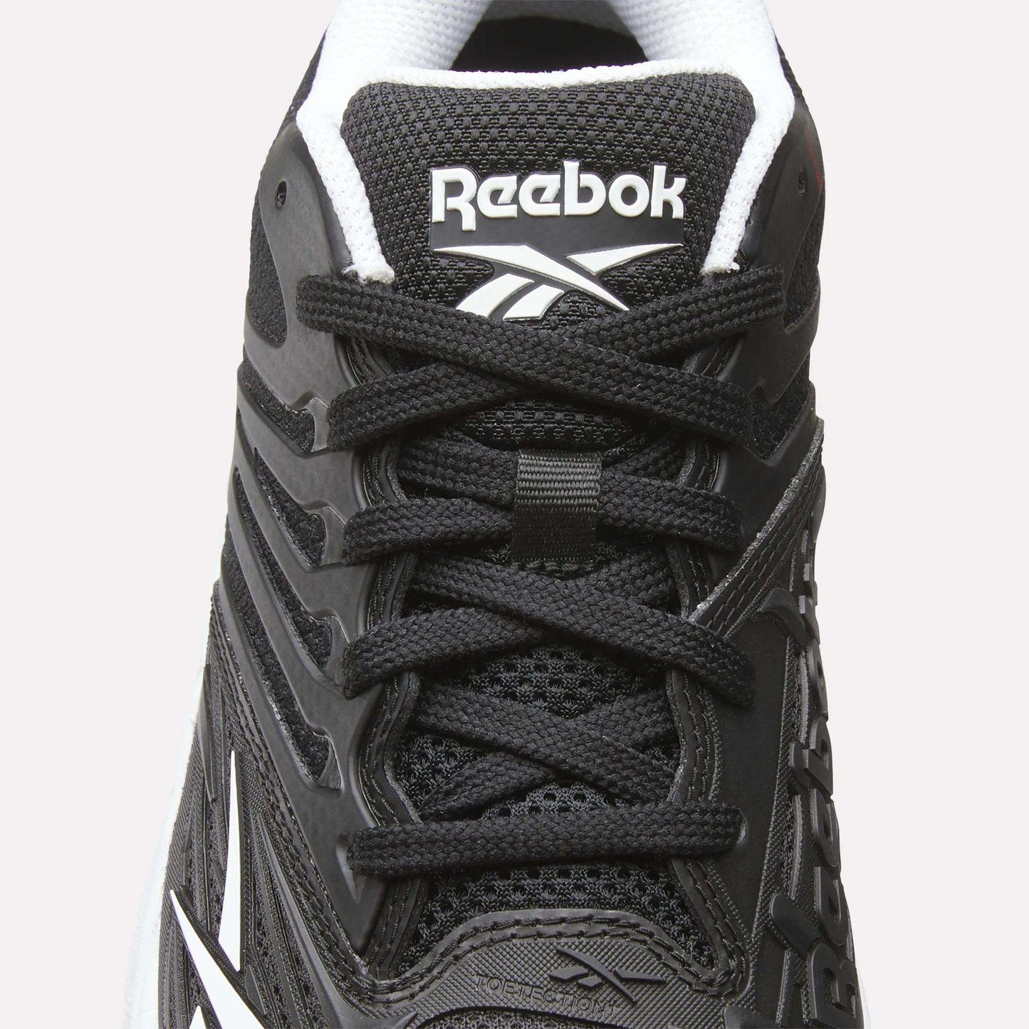 Close-up of the Women's Phase Evo Tennis Shoes by Reebok in black with white accents, featuring laces, mesh texture, side design, and the Reebok logo on the tongue.