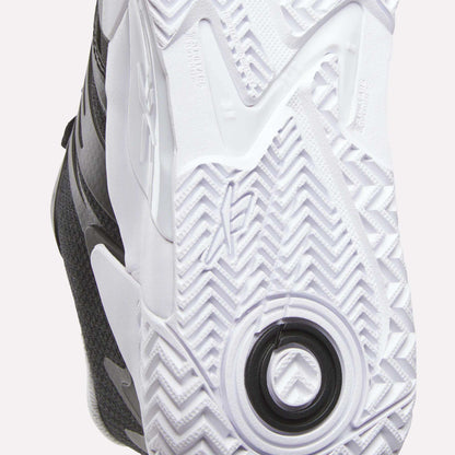 Close-up of the white rubber outsole on Reebok Women's Phase Evo Tennis Shoes, featuring a herringbone tread, circular heel detail, and textured grip for traction and support—ideal for long-lasting tennis performance.