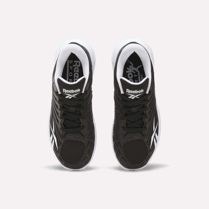 A pair of Reebok Women's Phase Evo Tennis Shoes in black with white accents is shown from above on a light background, featuring the Reebok logo on the tongue and side.