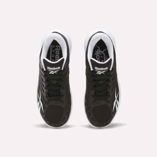 A pair of Reebok Women's Phase Evo Tennis Shoes in black with white accents is shown from above on a light background, featuring the Reebok logo on the tongue and side.