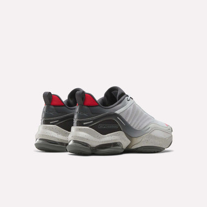 The Reebok Mita Sneakers x DMX Series 3000 Shoes feature a chunky modern design with gray, white, and black tones, red accents, thick speckled soles with DMX moving air tech—shown from the back and side against a plain white background.