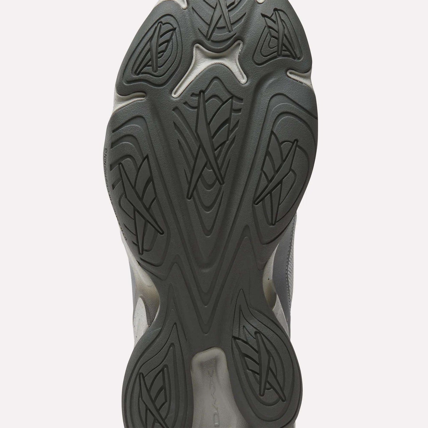 Close-up of the black rubber outsole on the Reebok Mita Sneakers x DMX Series 3000 Shoes, showing an intricate pattern of curved lines and geometric shapes for traction, enhanced with Reebok’s DMX moving air technology.