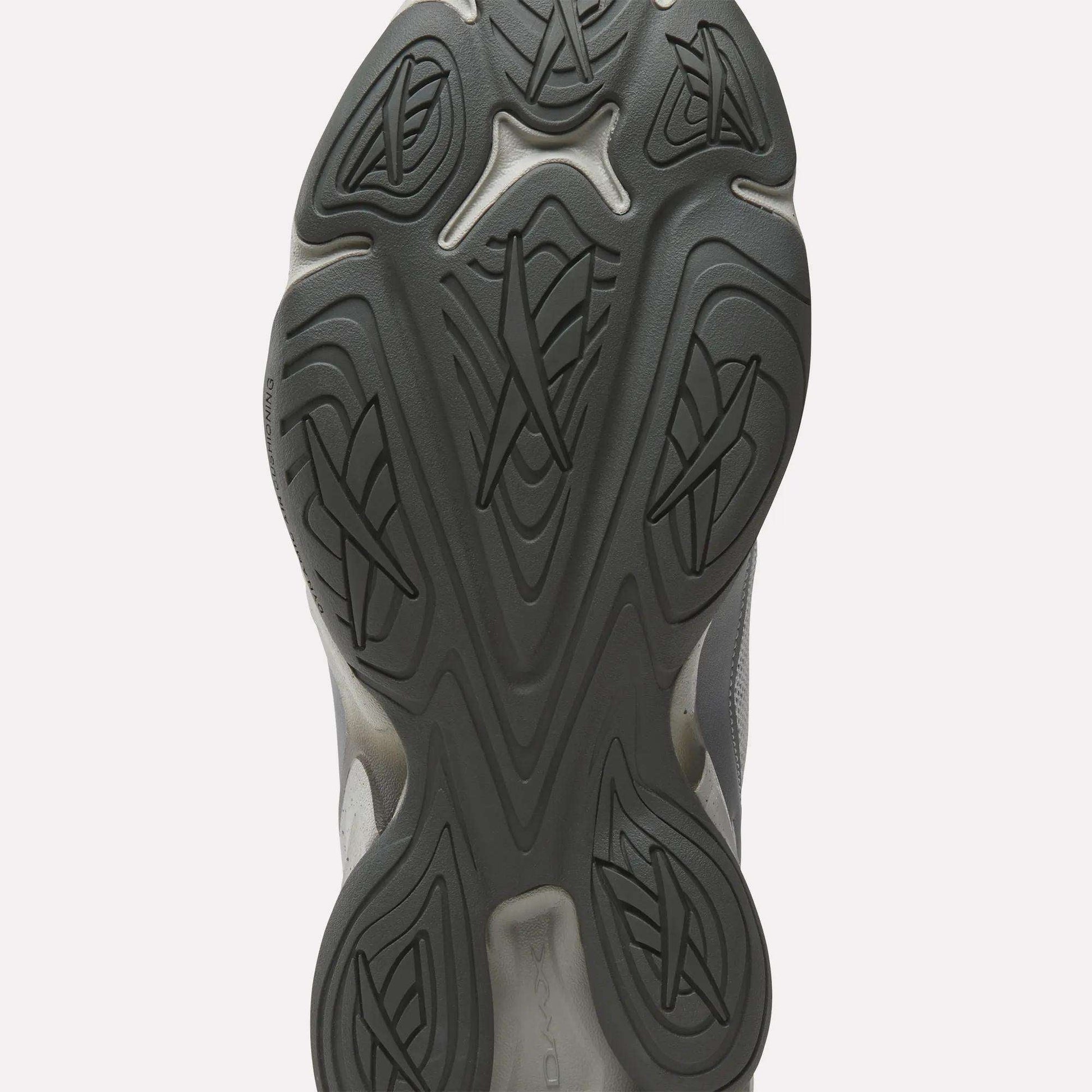 Close-up of the black rubber outsole on the Reebok Mita Sneakers x DMX Series 3000 Shoes, showing an intricate pattern of curved lines and geometric shapes for traction, enhanced with Reebok’s DMX moving air technology.