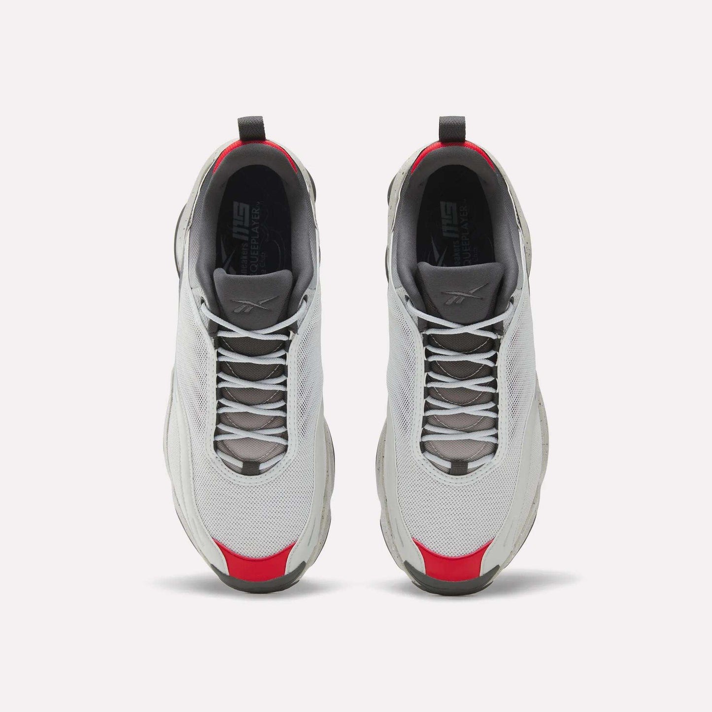 A pair of white Reebok Mita Sneakers x DMX Series 3000 athletic shoes with gray soles and laces, red accents on the toe and heel, and DMX moving air technology, seen from above on a white background.