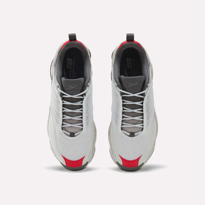 A pair of white Reebok Mita Sneakers x DMX Series 3000 athletic shoes with gray soles and laces, red accents on the toe and heel, and DMX moving air technology, seen from above on a white background.