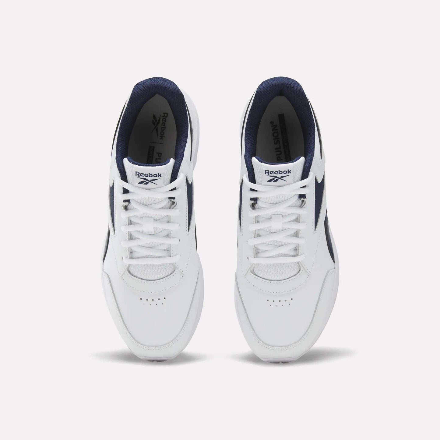 A top-down view of the Men's Walk Ultra 7 DMX Max Shoes by Reebok, featuring a white design with navy blue accents and DMX cushioning, displays the tops and laces of both shoes against a plain white background.