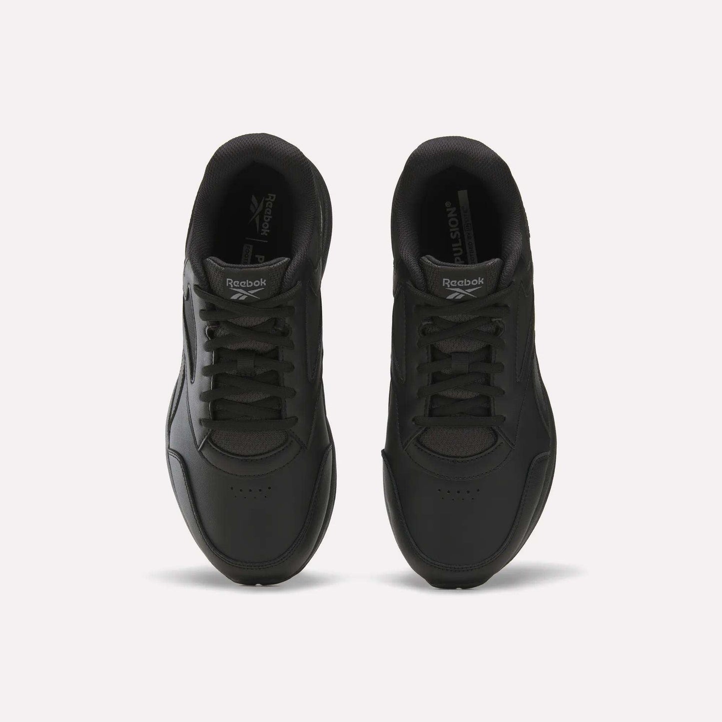 A pair of black Men's Walk Ultra 7 DMX Max Shoes - Wide 4E by Reebok is shown from above, highlighting the laces, toe area, and Reebok branding on the tongues, set against a plain white background. These wide-fit walking shoes are equipped with DMX cushioning for added comfort and support.