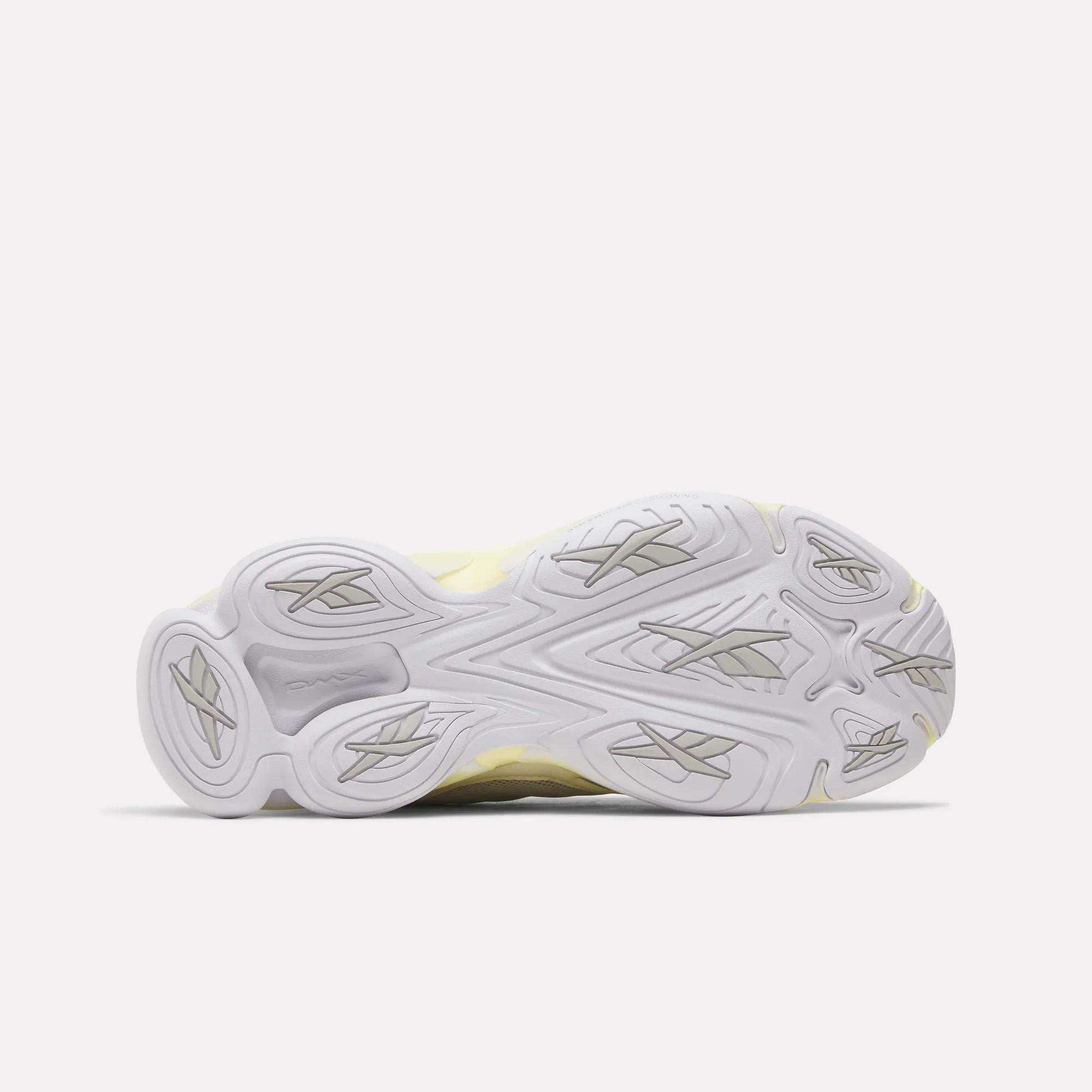 The image displays the bottom view of the Reebok Women's DMX Series 3000 Training Shoes, showcasing a white and light gray rubber outsole with multiple textured grooves and patterns for enhanced traction. This sole design is characteristic of Reebok's DMX 3 Technology, which provides added comfort and support for those seeking cushioned training footwear.