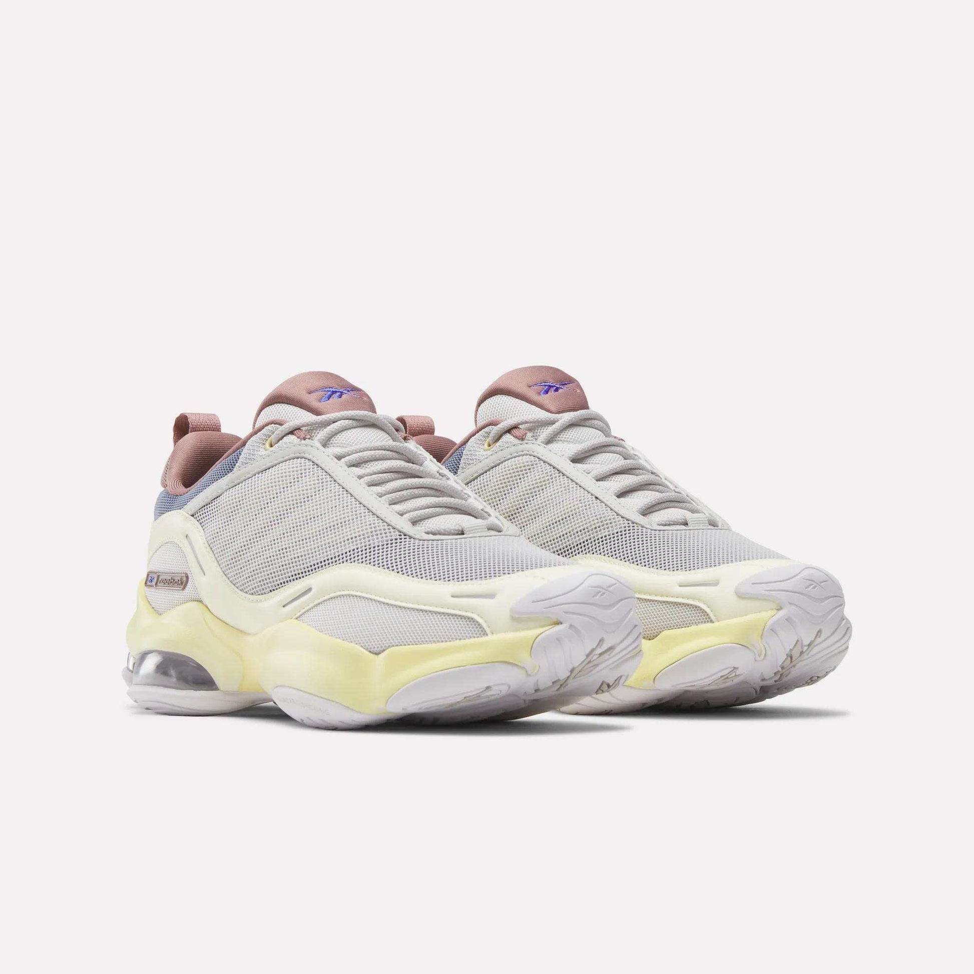 The Reebok Women's DMX Series 3000 Training Shoes feature white mesh uppers with pale yellow and lavender accents, chunky soles, and visible air cushioning enhanced by DMX 3 Technology, displayed against a plain white background.