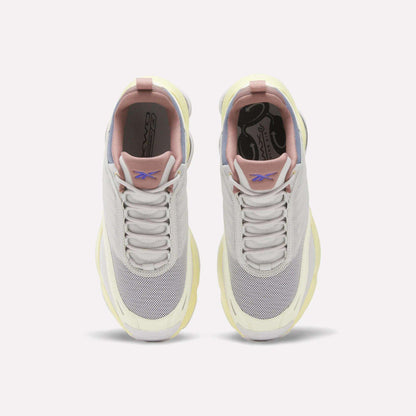 A top view of the Reebok Women's DMX Series 3000 Training Shoes in light gray and white, featuring pink and pale yellow accents, mesh toe boxes, and the Reebok logo on the tongue. These cushioned shoes are designed with innovative DMX 3 Technology and are displayed side by side on a plain white background.