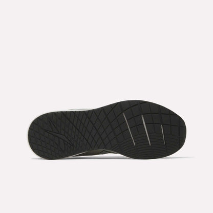 The image displays the black rubber outsole of a Reebok Men's Nanoflex 2 Training Shoe, highlighting its geometric tread pattern and several horizontal flex grooves, set against a plain white background.