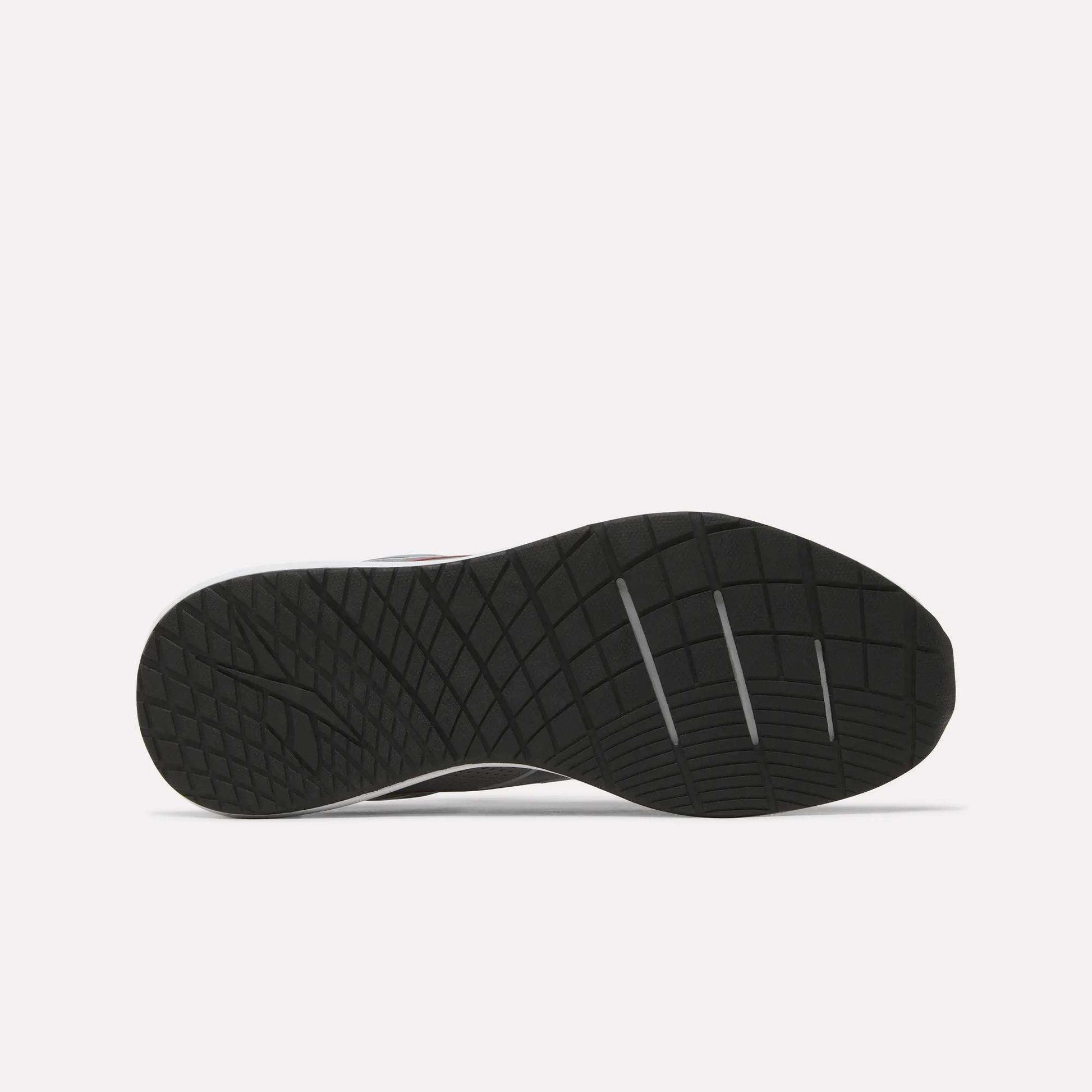 The image displays the black rubber outsole of the Men's Nanoflex 2 Training Shoes by Reebok, featuring a geometric traction pattern and three deep horizontal grooves for enhanced flexibility. The background is plain white.