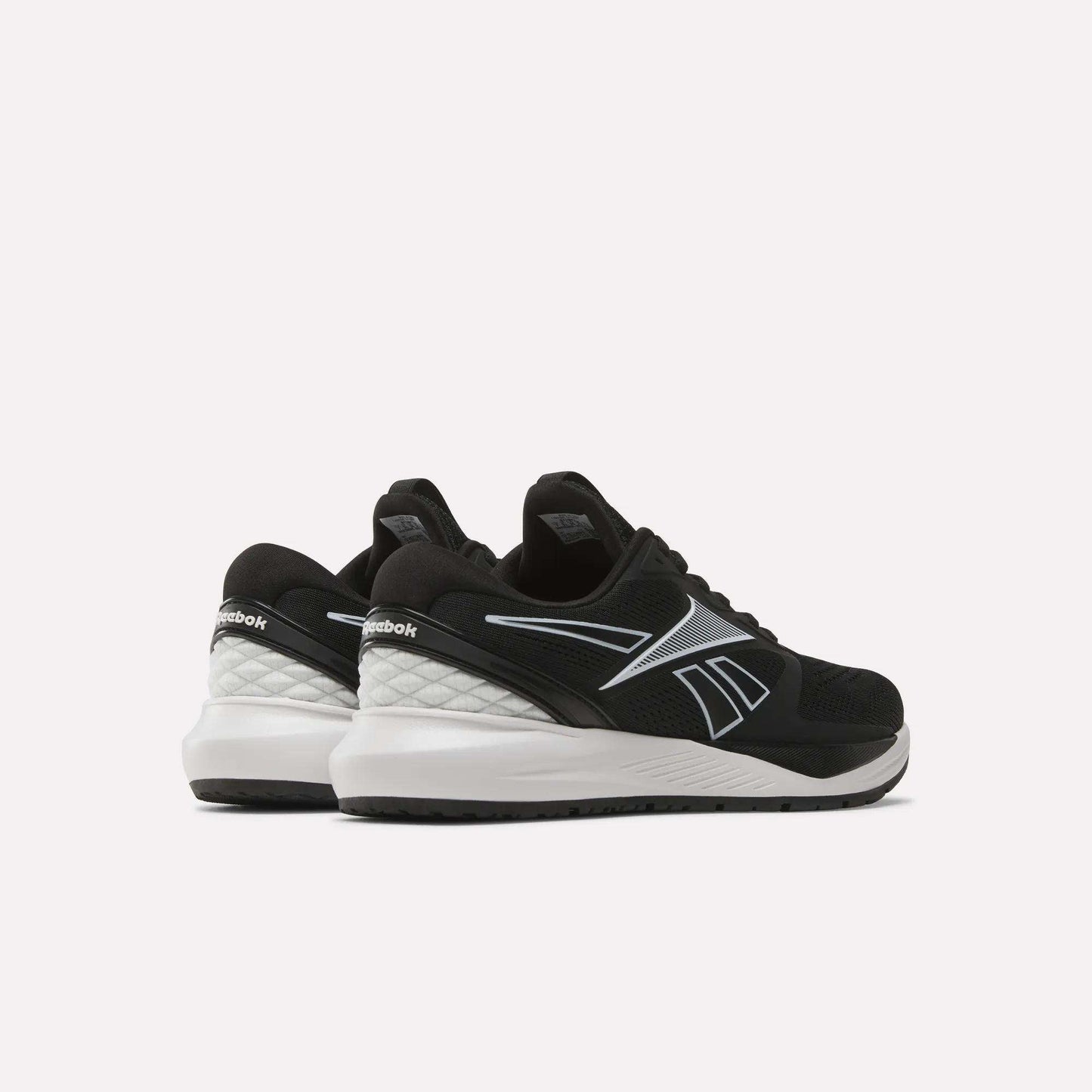 A pair of Women's NFX Trainer 2 Training Shoes by Reebok, featuring black uppers with white soles and silver accents, displayed from a rear side angle on a plain white background.