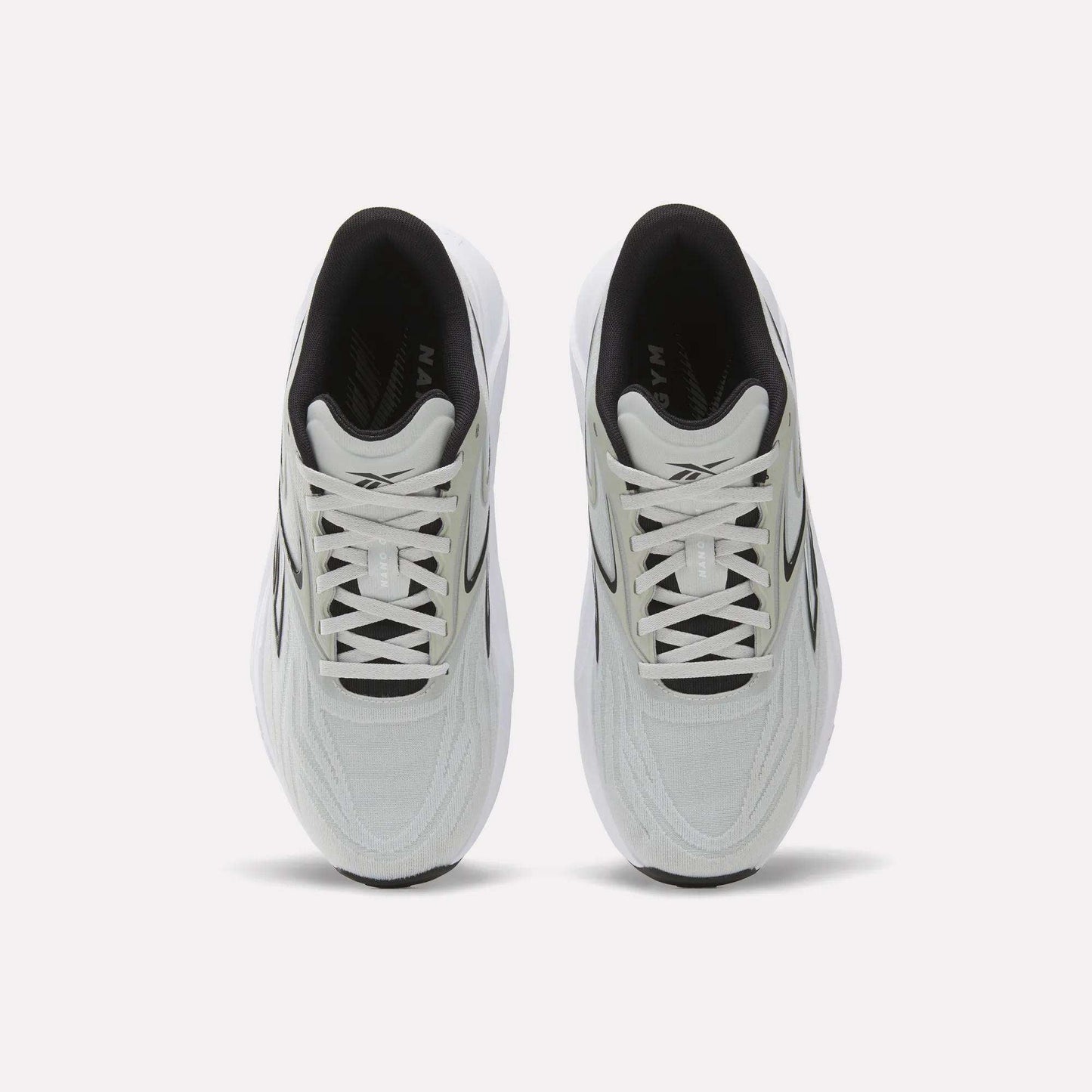 A top view of Reebok Nano Gym 2.0 Training Shoes shows a white pair with black accents, white laces, a slightly chunky silhouette, and a comfortable black interior.