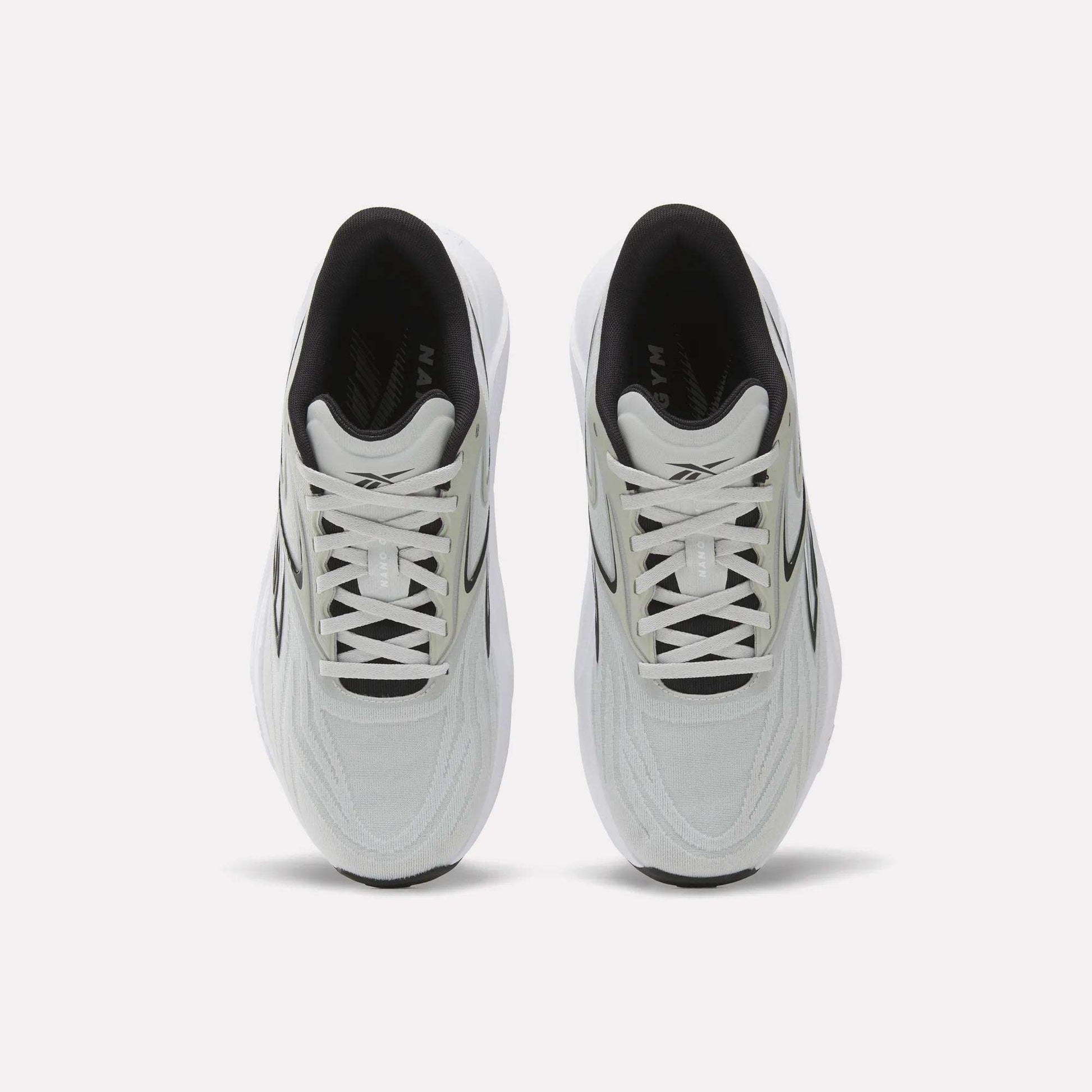 A top view of Reebok Nano Gym 2.0 Training Shoes shows a white pair with black accents, white laces, a slightly chunky silhouette, and a comfortable black interior.