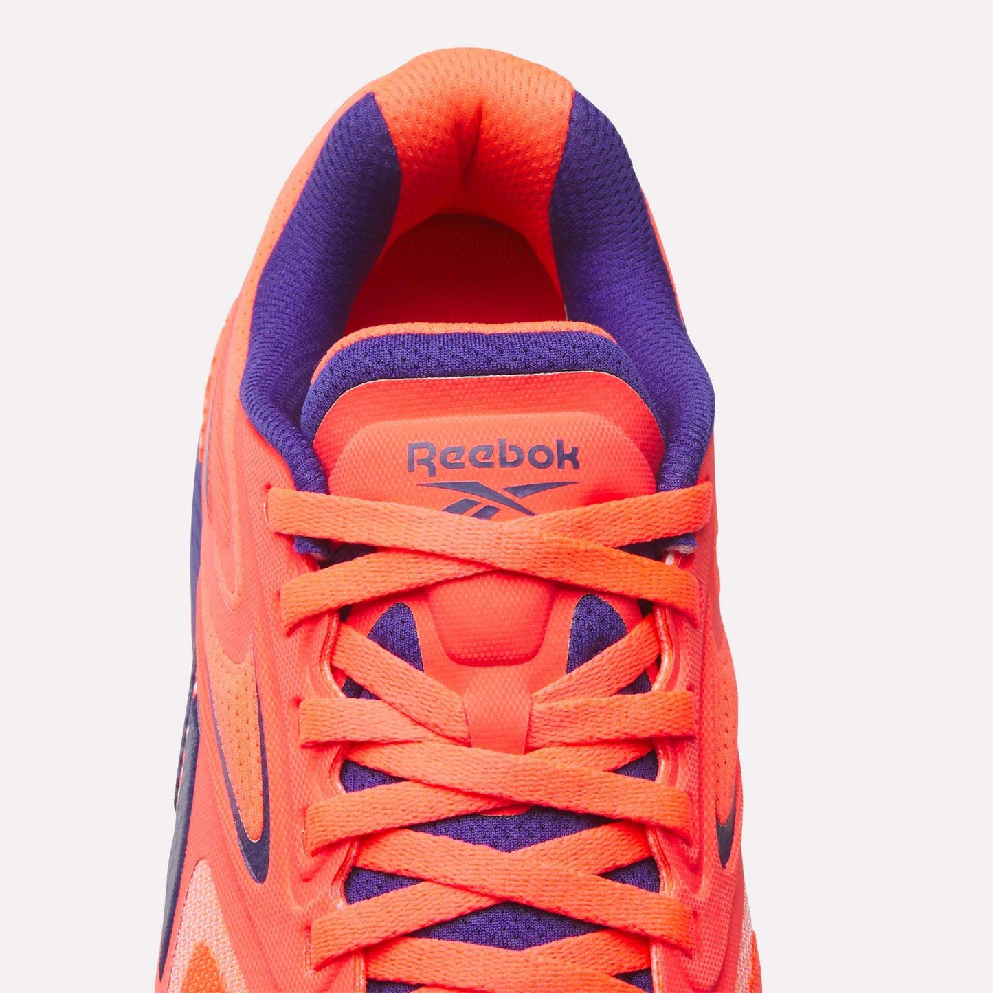 Top view of Reebok Women's Nano X5 Edge Training Shoe in bright orange and purple with orange laces, purple inner lining, and the Reebok logo on the tongue—ideal for your next HIIT class.