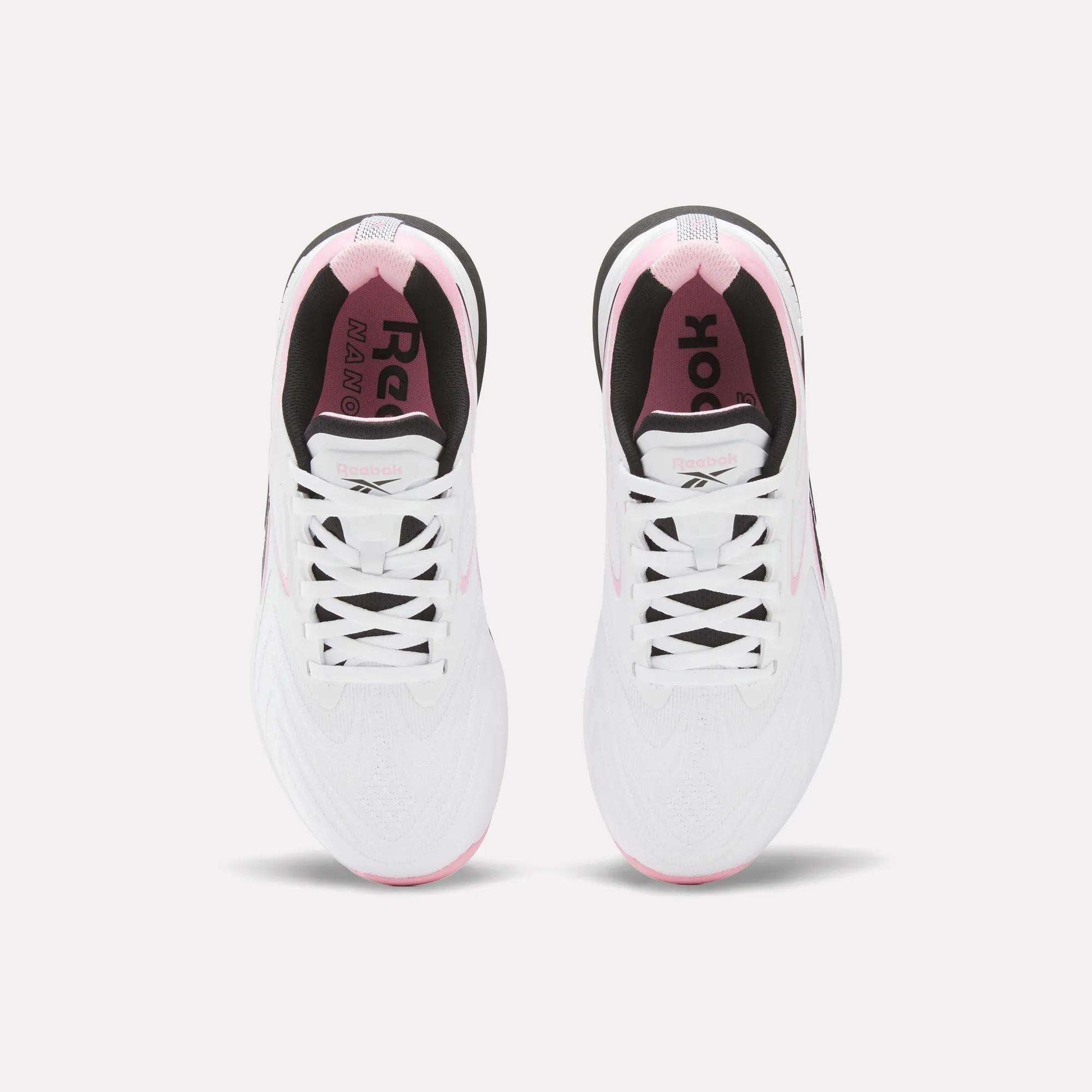 Top view of Reebok Women's Nano X5 Edge Training Shoes in white with pink accents, black inner lining, and visible laces, shown side by side on a light background.