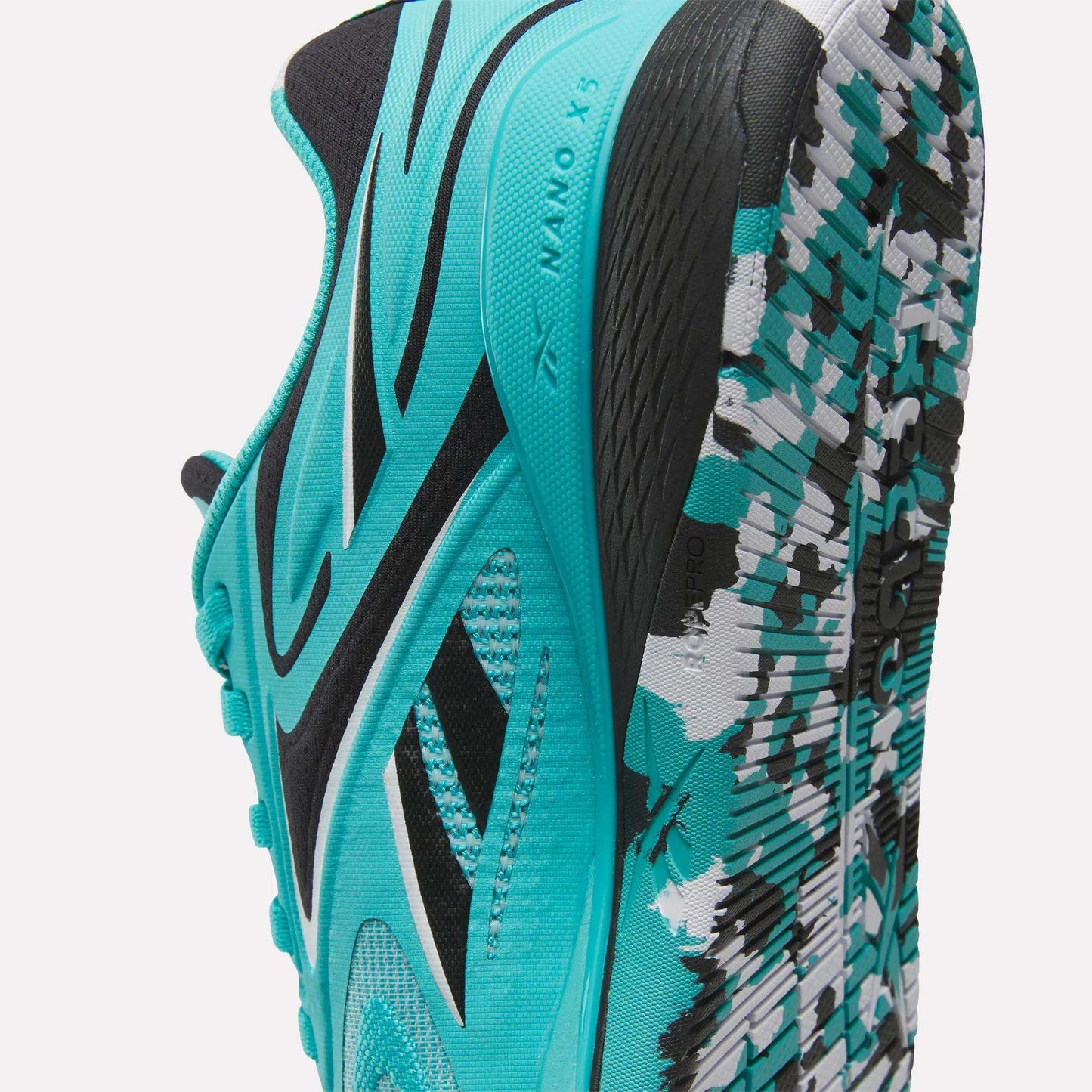 A close-up of the Reebok Women's Nano X5 Edge Training Shoes in turquoise and black, featuring side branding, mesh texture, and a patterned sole with white, black, and turquoise accents—perfect for HIIT classes.