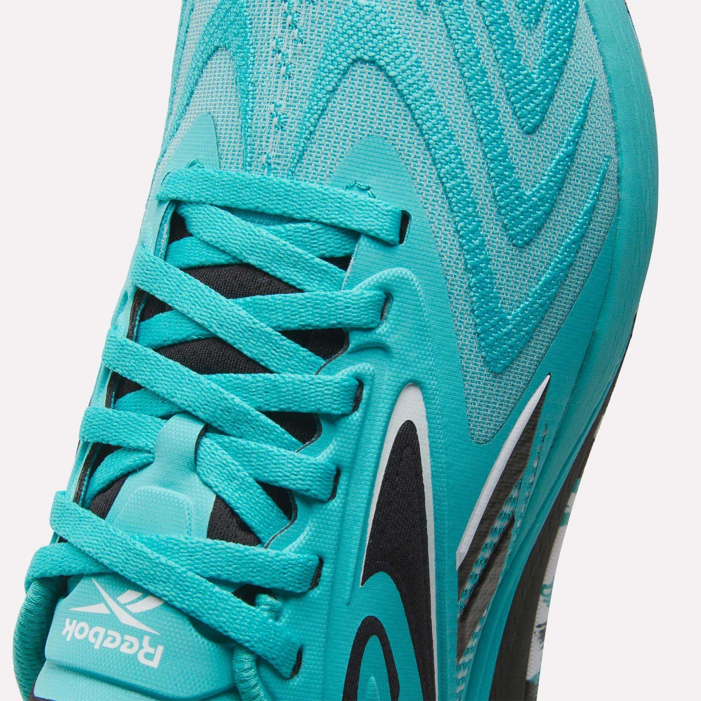 Close-up of Reebok Women's Nano X5 Edge Training Shoes in turquoise, highlighting the laces, Reebok logo on the tongue, and wave-like pattern—perfect for HIIT classes and dynamic workouts.