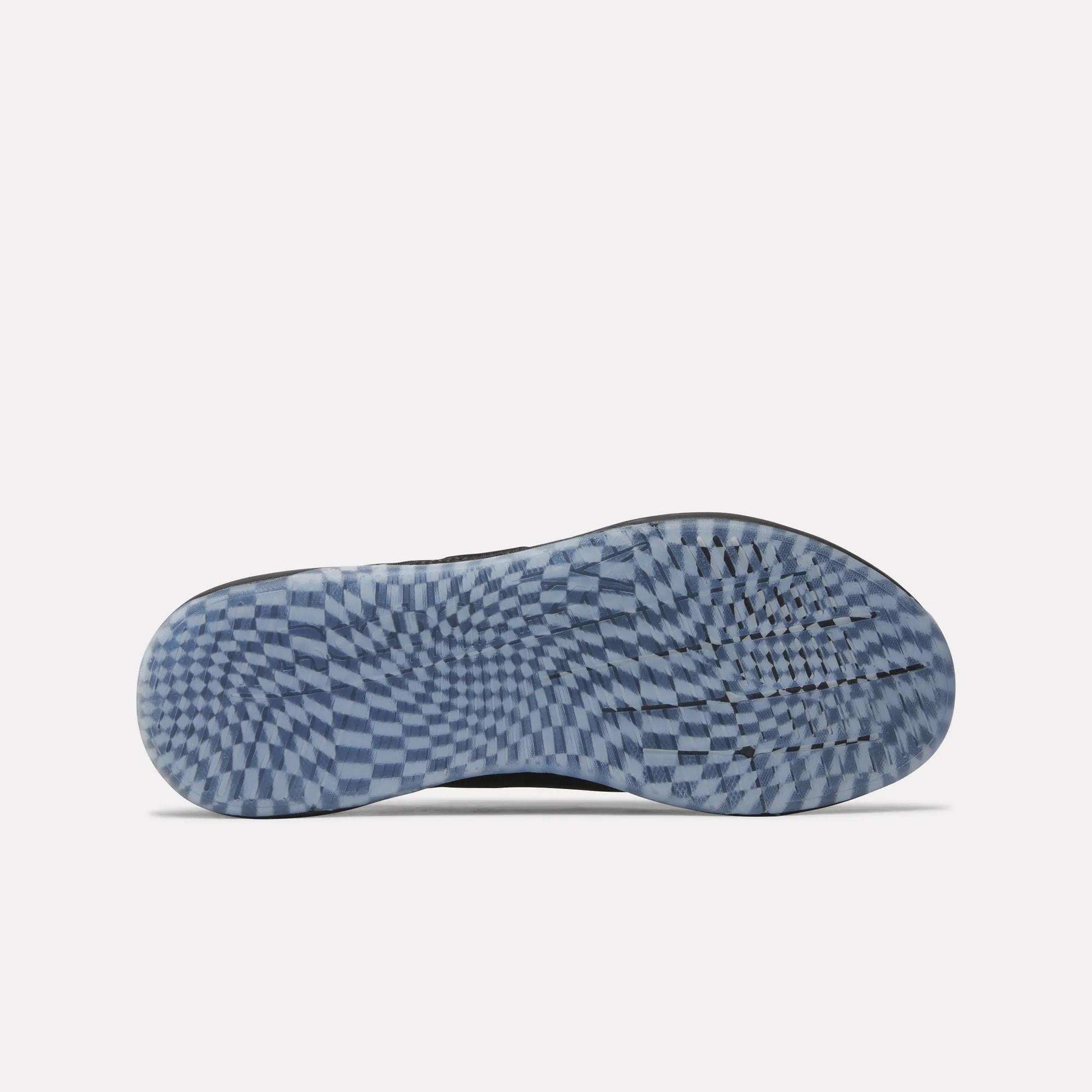 The image shows the sole of a Nano X5 Edge Training Shoe by Reebok, featuring a blue and white checkered pattern with an optical illusion effect. Designed for performance, these stylish training shoes display the Reebok logo near the middle.