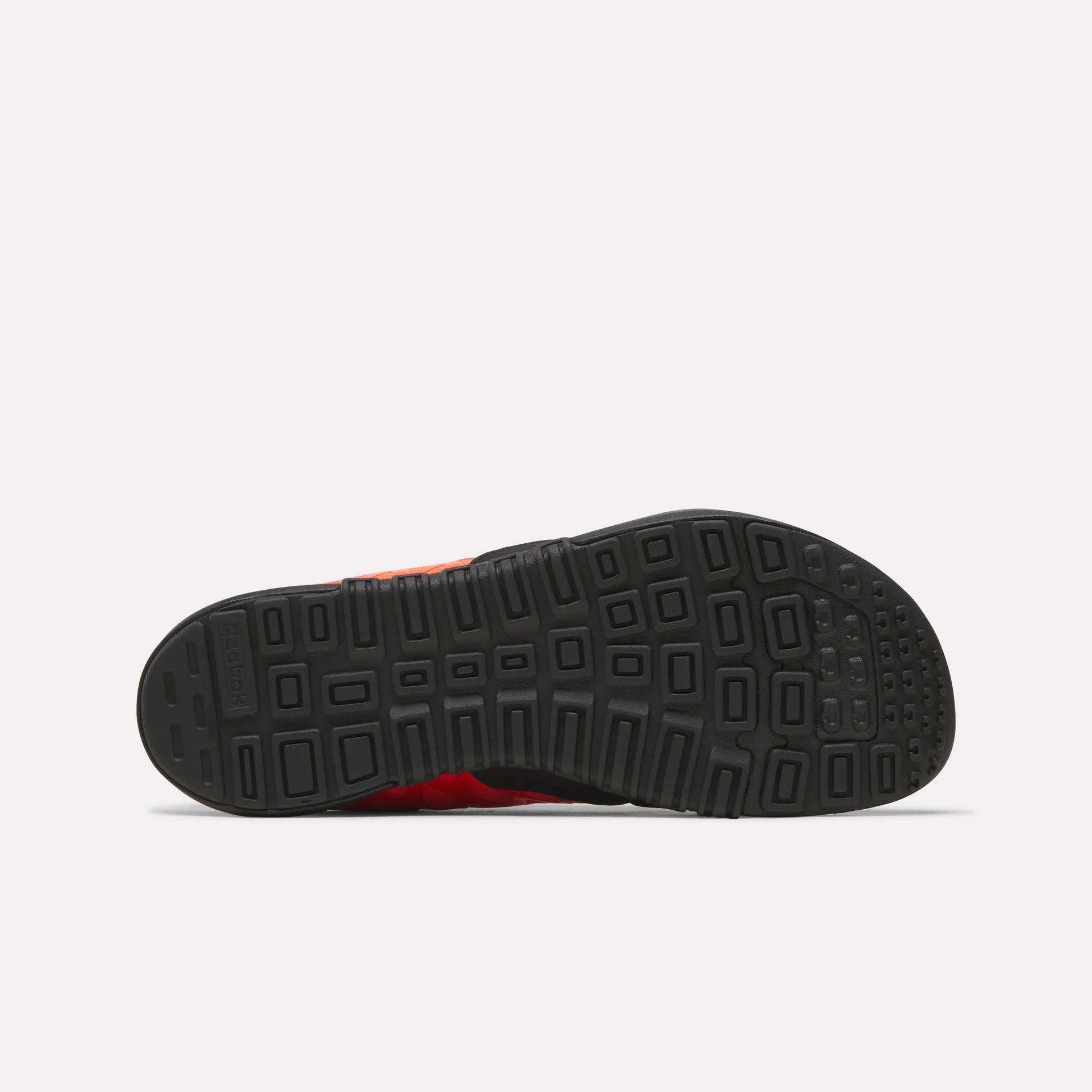 The image displays the bottom view of a black rubber sole from Reebok Men's Nano 2.0 Training Shoes, showing a geometric tread pattern against a plain, light-colored background.