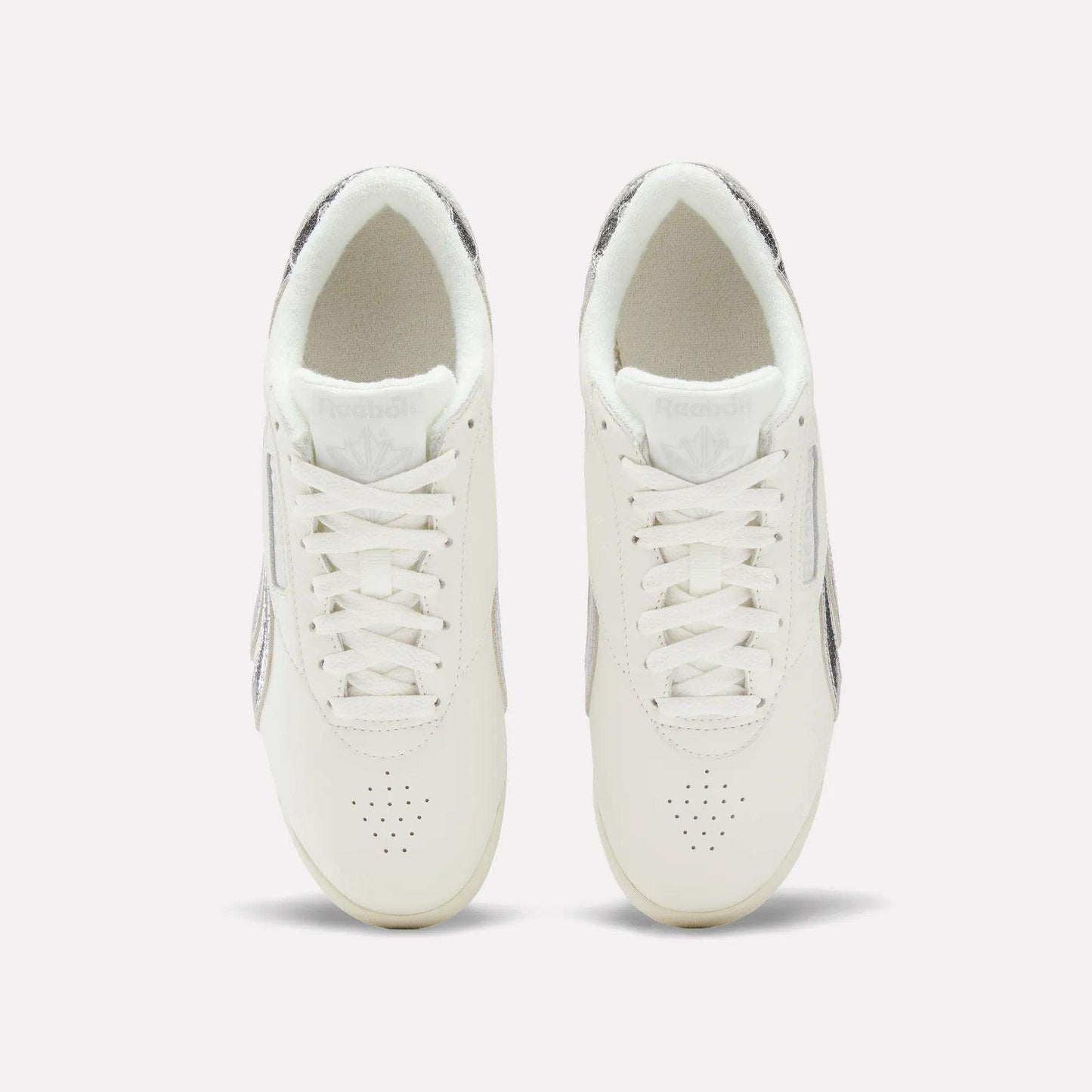 Top view of Reebok Women's Freestyle Lo Shoes with laces and subtle metallic accents on the sides and heel, displayed against a simple light background.