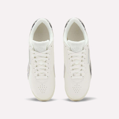 Top view of Reebok Women's Freestyle Lo Shoes with laces and subtle metallic accents on the sides and heel, displayed against a simple light background.