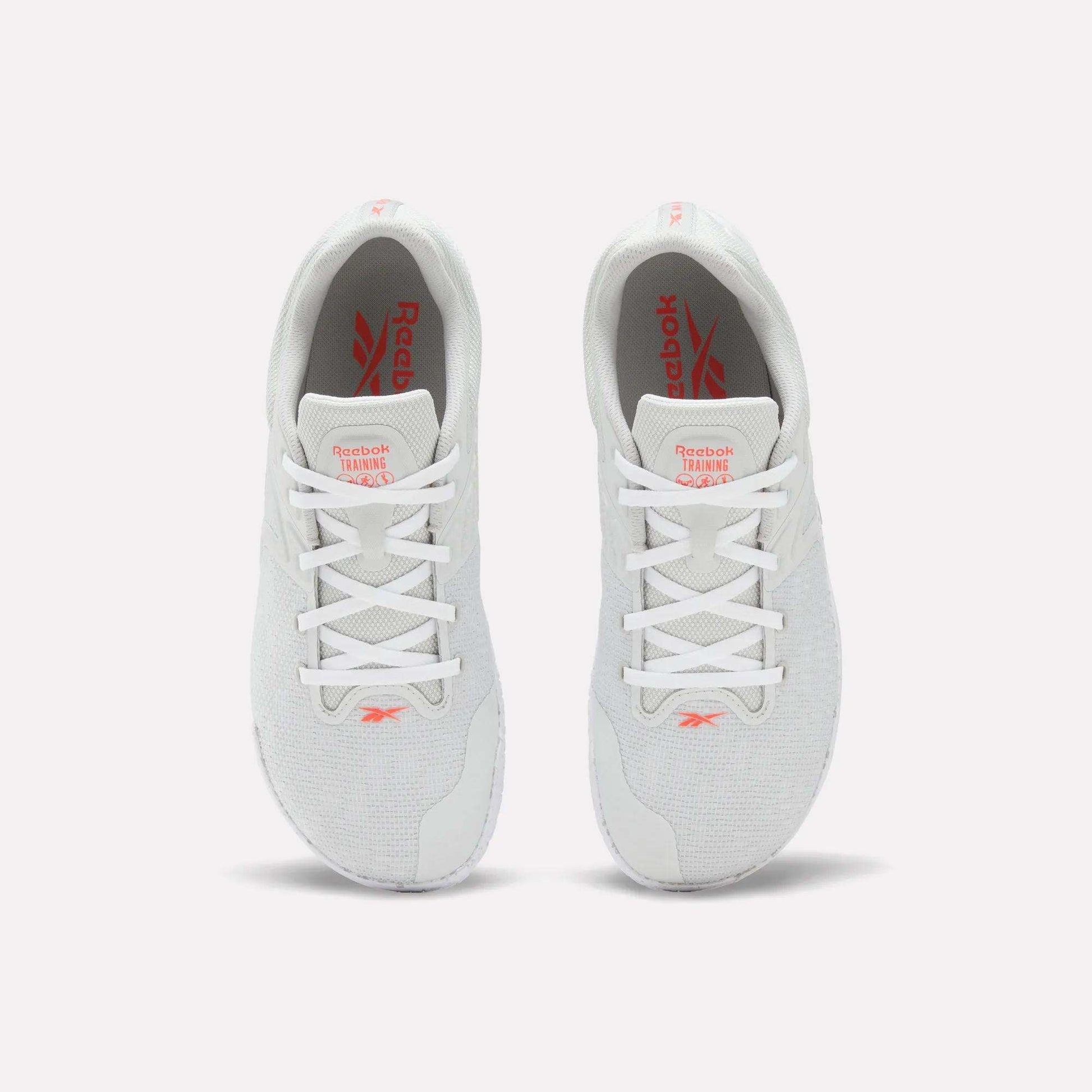 A pair of white Reebok Nano Zero Training Shoes, shown from above on a plain white background, feature red Reebok branding on the tongue and insole, white laces, a breathable mesh upper, and a zero-drop design.