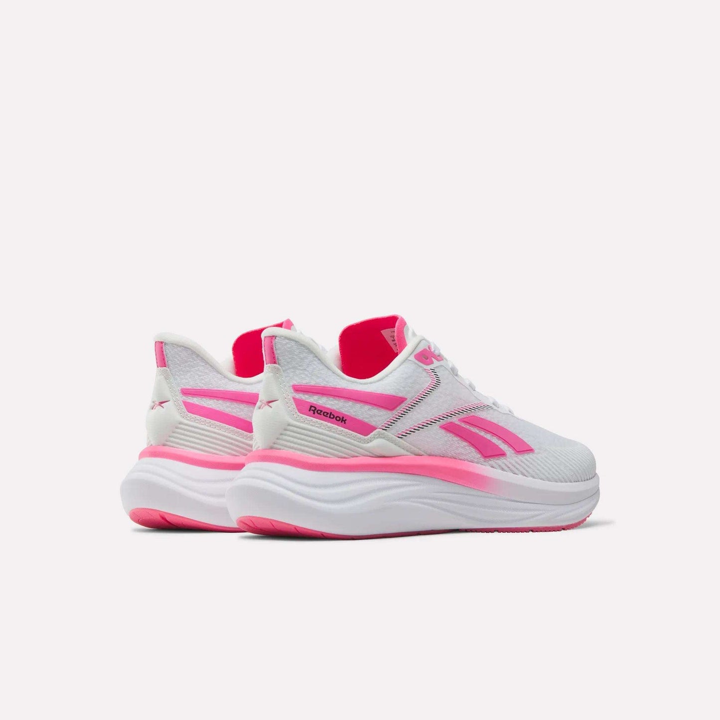 A pair of Reebok Women's Viva Speed Shoes in white with pink accents and thick soles, designed with a cushioned midsole for enhanced comfort, displayed from the side and slightly behind on a plain light background.