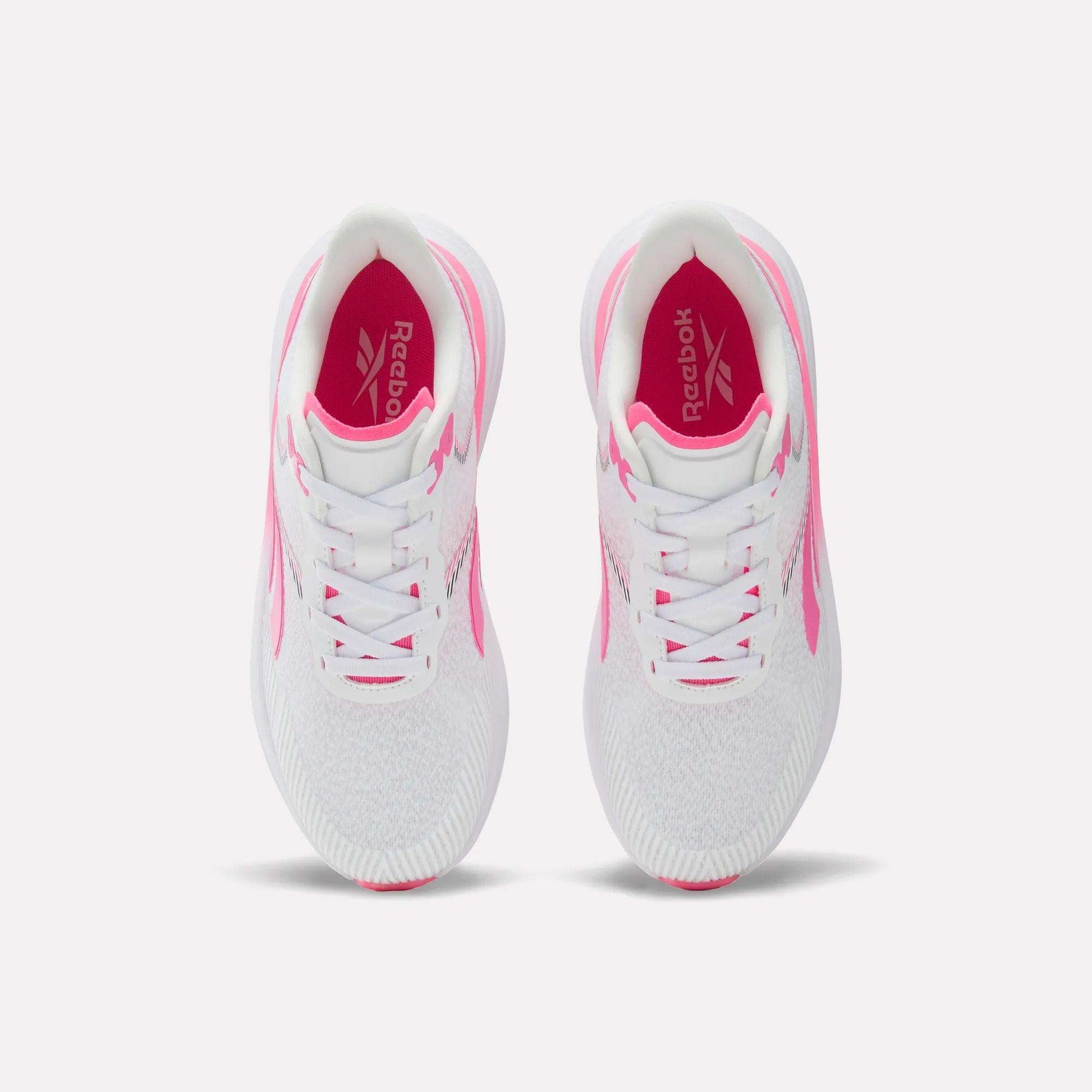 A pair of Women's Viva Speed Shoes by Reebok in white with pink accents, shown from above on a white background. These breathable shoes feature white laces, a cushioned midsole for all-day comfort, and a pink Reebok logo on the insoles.