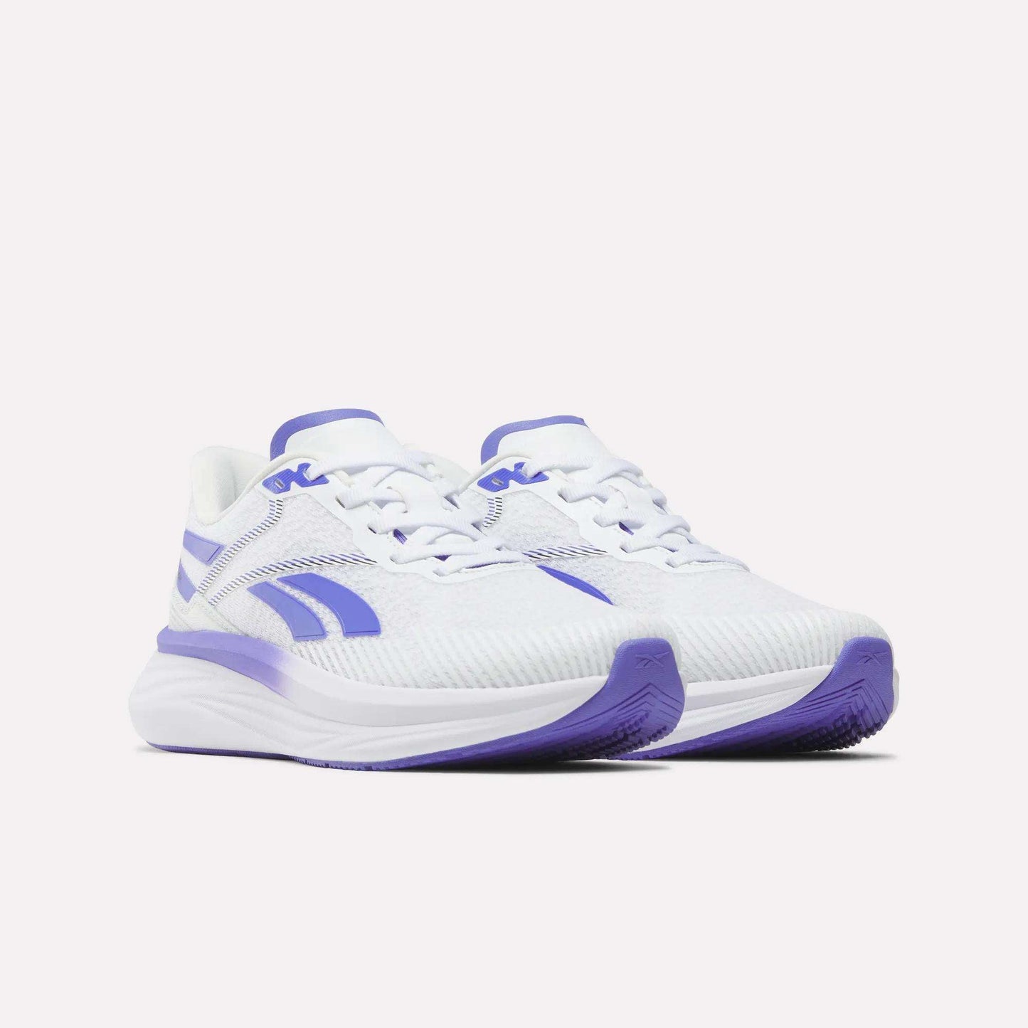 Introducing the Reebok Women's Viva Speed Shoes: a stylish pair of white athletic sneakers highlighted with vibrant purple accents on the sole, logo, and detailing. Featuring a cushioned design and breathable mesh texture for enhanced comfort, these sneakers are ideal for your active lifestyle. Shown here against a plain white background.