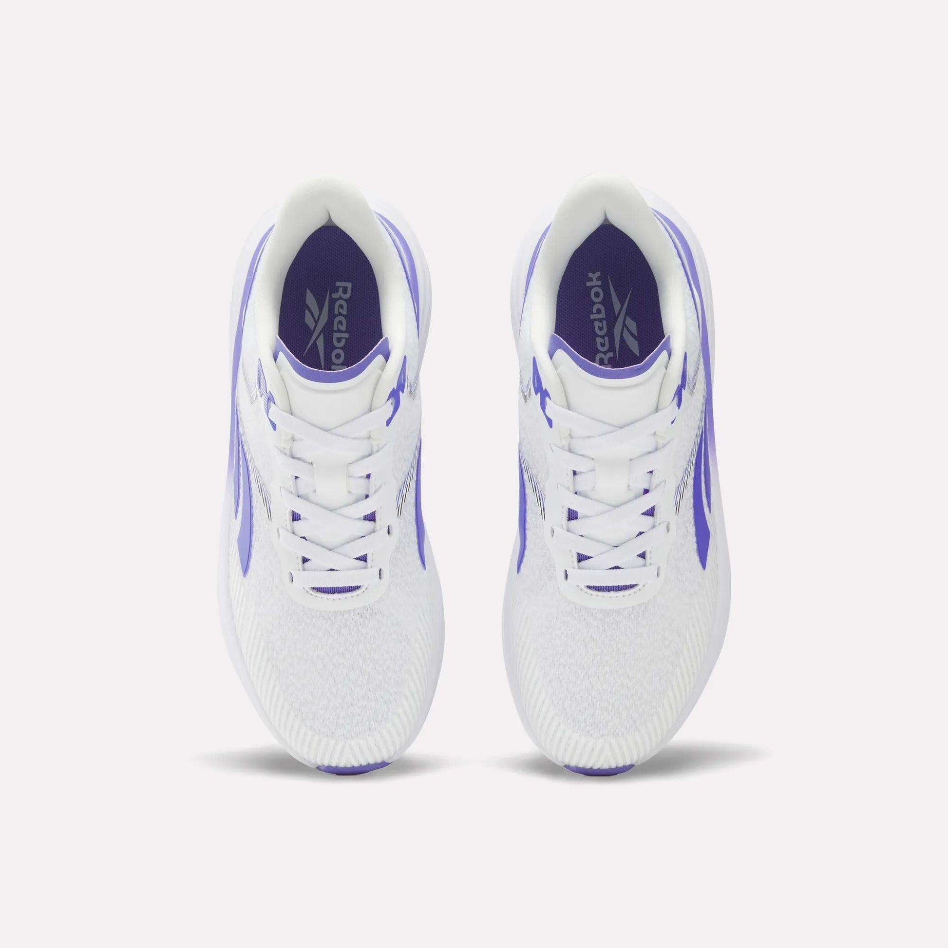 Top view of a pair of Reebok Women's Viva Speed Shoes featuring purple accents and Reebok logos on the insoles, placed side by side on a plain white background. These cushioned sneakers are crafted for comfort and style, making them perfect for active lifestyles.