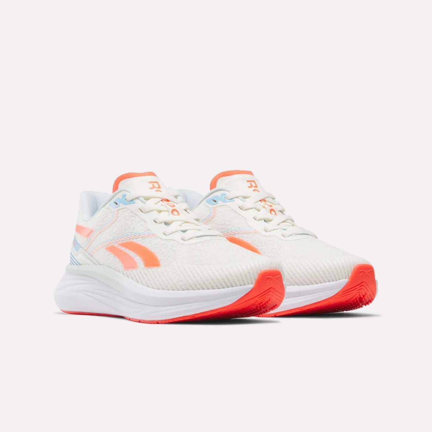 Introducing the Women's Viva Speed Shoes by Reebok—a stylish pair of white athletic sneakers with vibrant orange and light blue accents. Featuring a thick white sole with an orange tread, these shoes are cushioned for maximum comfort and enhanced breathability, making them perfect for active days. The Women's Viva Speed Shoes are displayed side by side on a plain white background.