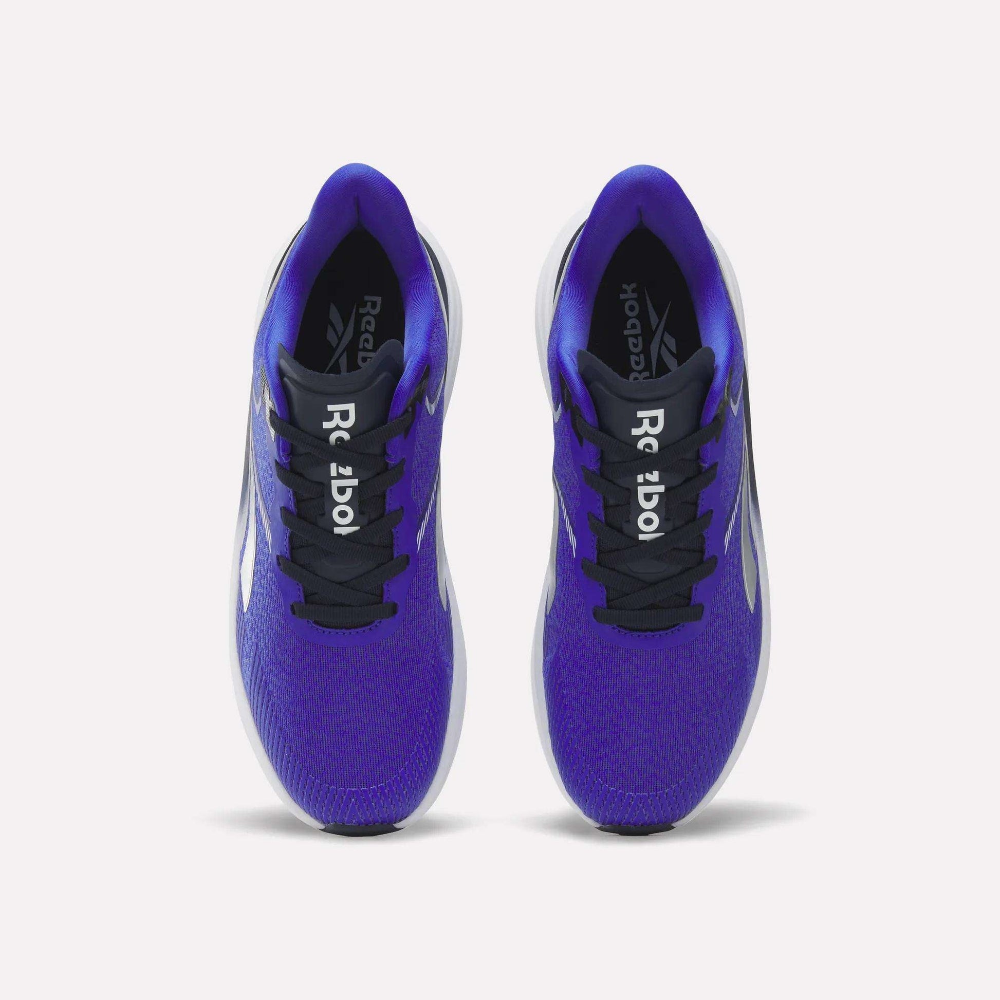 A pair of blue Reebok Men's Viva Speed Shoes viewed from above. These shoes feature black laces, black tongues with white Reebok logos, and white midsoles. Designed for added comfort with cushioned support, the insides display the brand name in white on a black background.