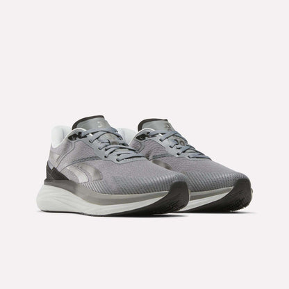 A pair of Reebok Men's Viva Speed Shoes in gray and white, featuring mesh uppers, cushioned white soles, and black accents, are displayed on a plain white background. These breathable shoes offer enhanced comfort with their cushioned soles, making them ideal for athletic activities.