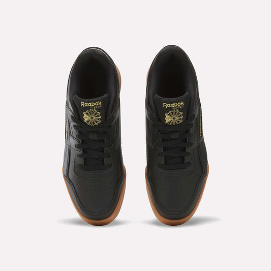 Top view of Reebok Workout Plus Shoes for big kids in black with brown gum soles, gold branding, and a star logo on the tongue, side by side on a white background—a sporty pick for juniors.