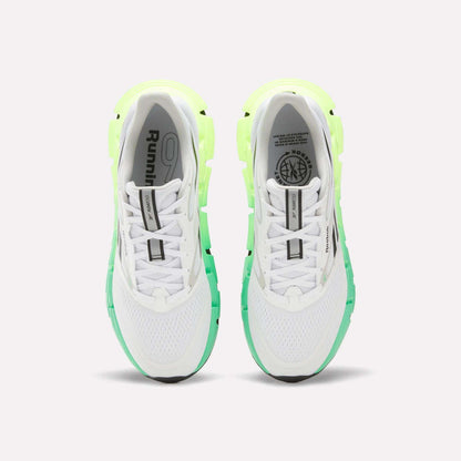 A top view of Reebok Men's FloatZig 2 Running Shoes in white with light green and neon yellow accents, Superfloat+ cushioning, black soles, and branding on the tongues and insoles, set against a plain white background.
