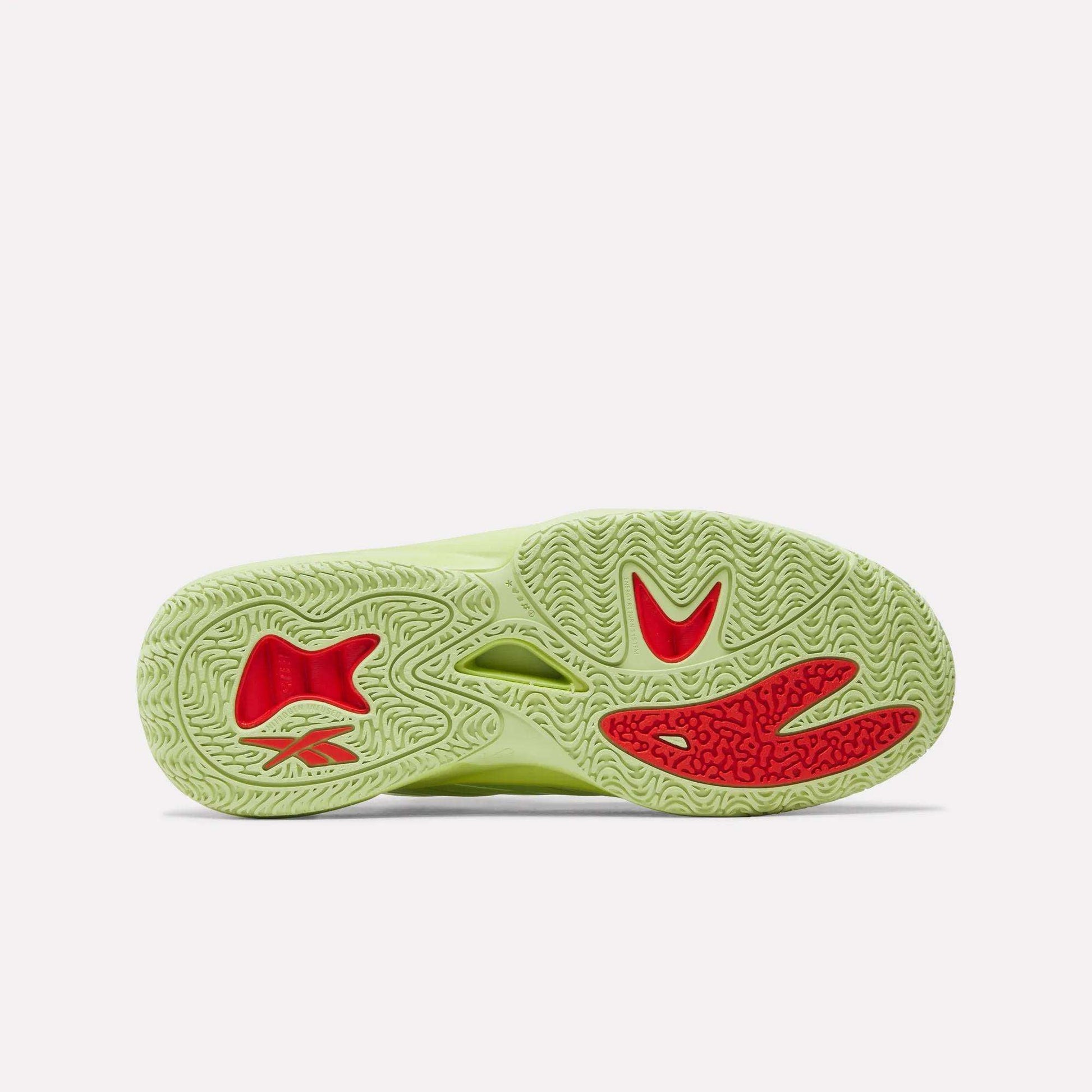 The image displays the sole of the Reebok Angel Reese 1 Basketball Shoes, featuring a light green color with textured patterns and bold red accents. It showcases the Energy Return System technology on a plain white background.